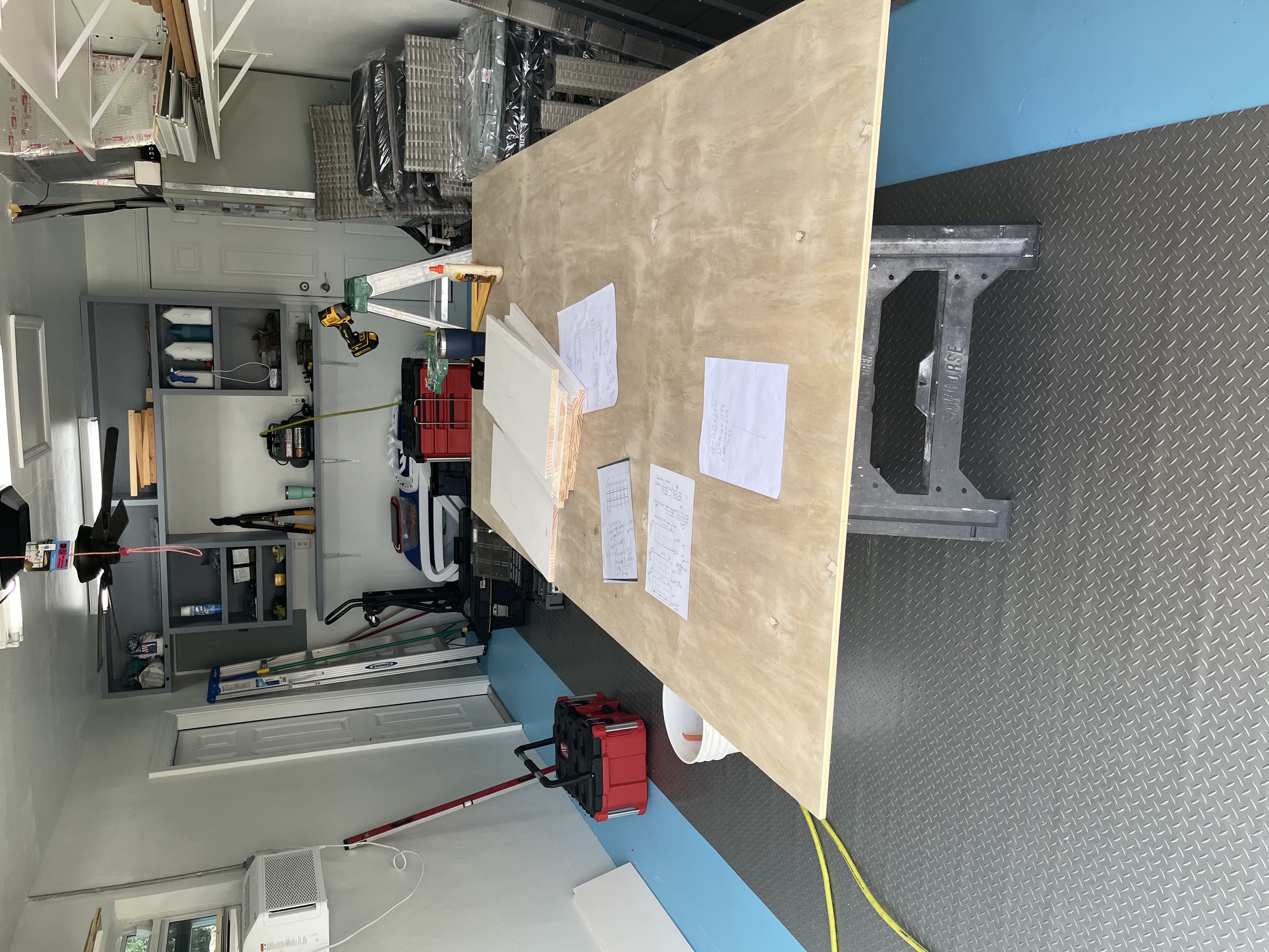 Large wood sheet and project plans laid out while preparing materials for custom shelving