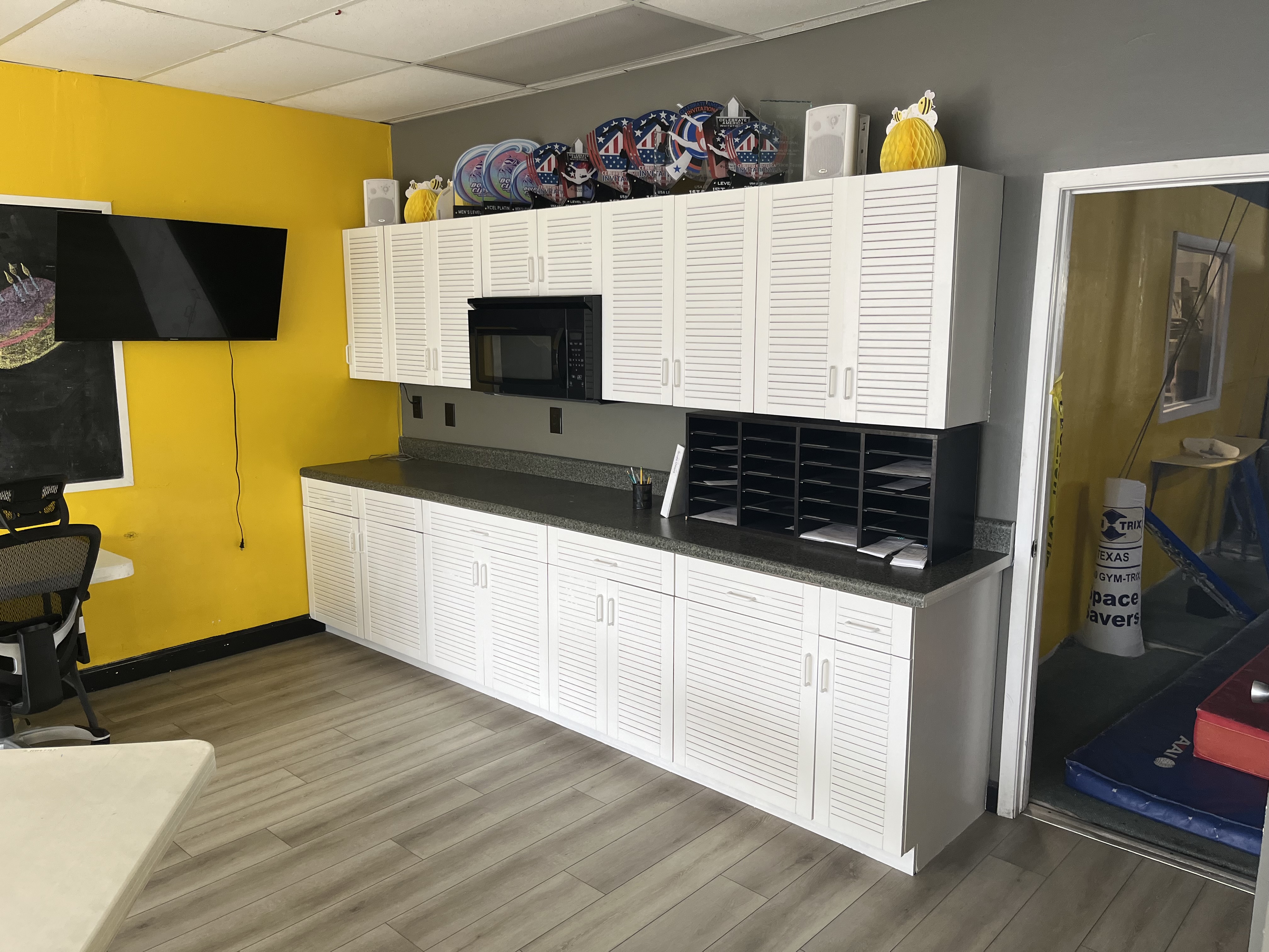 Completed white semi-gloss lower cabinet fronts and doors in the gymnastics gym