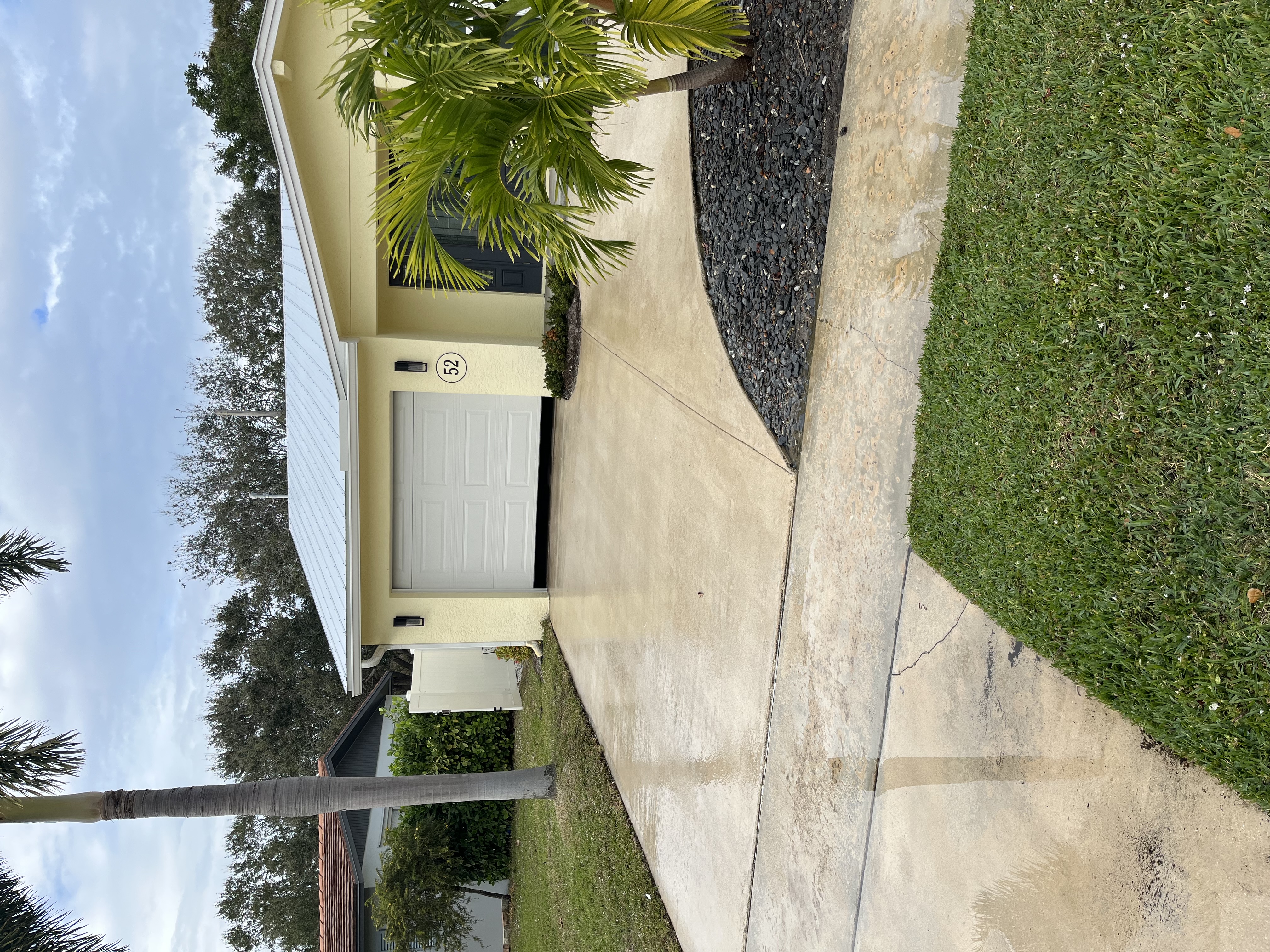 Finished exterior front view showing the driveway, garage approach, and dark stone landscape bed
