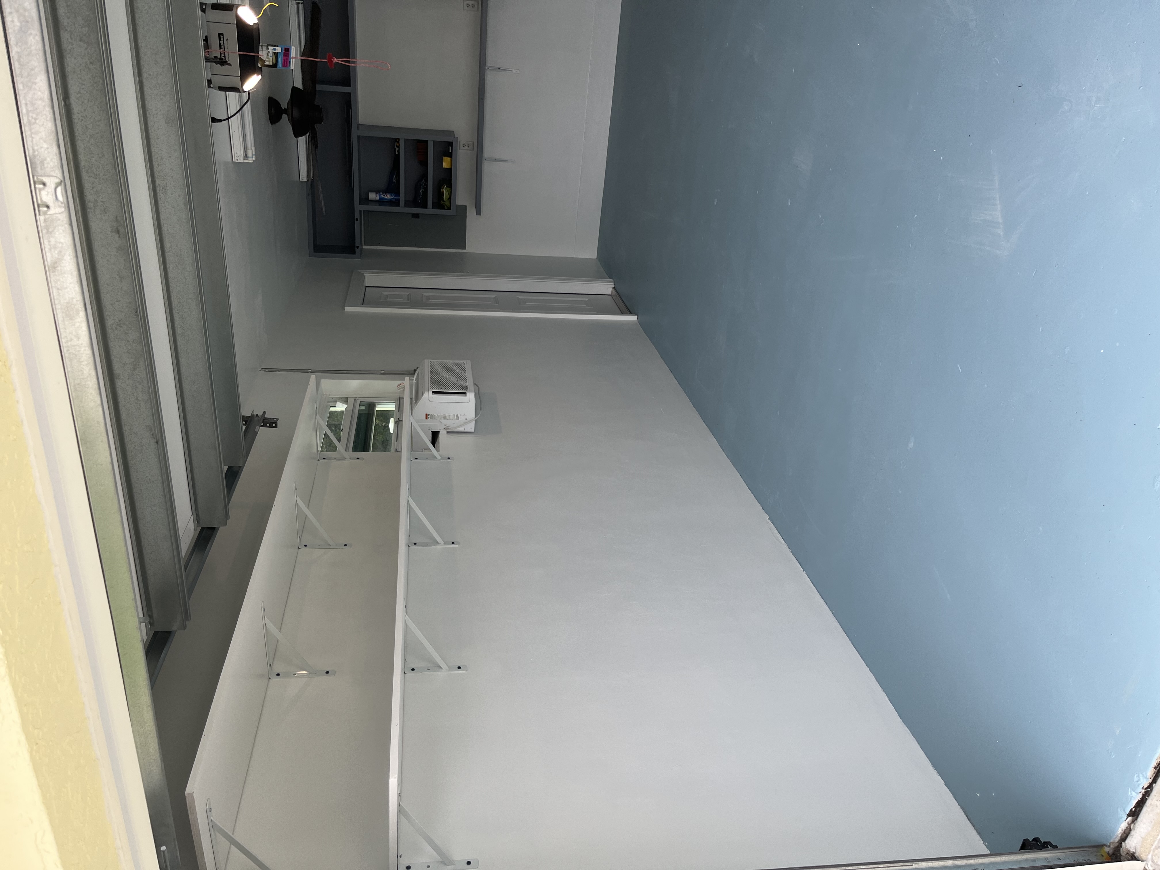 Garage floor after coating with a new clean blue finish applied across the slab