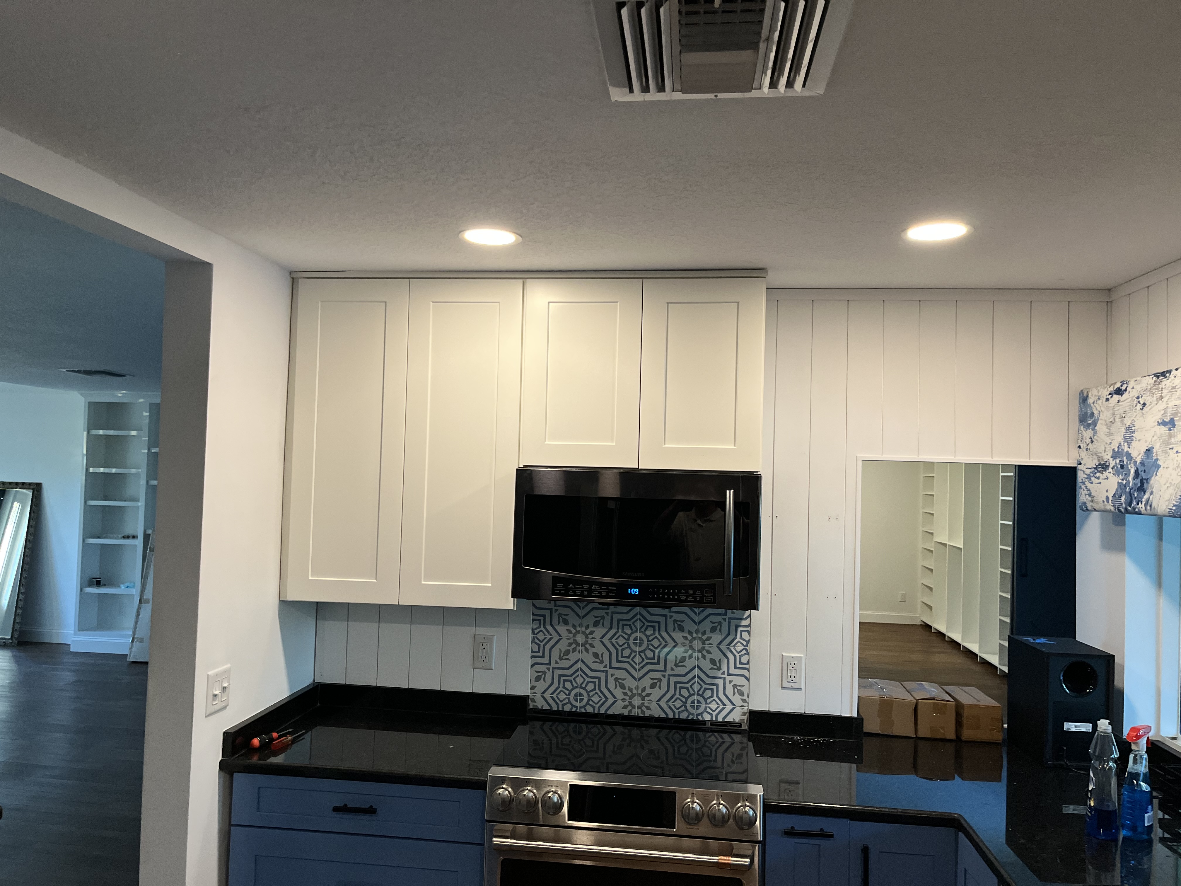 Finished kitchen view with wall paneling, upper cabinets, and backsplash installed around the range