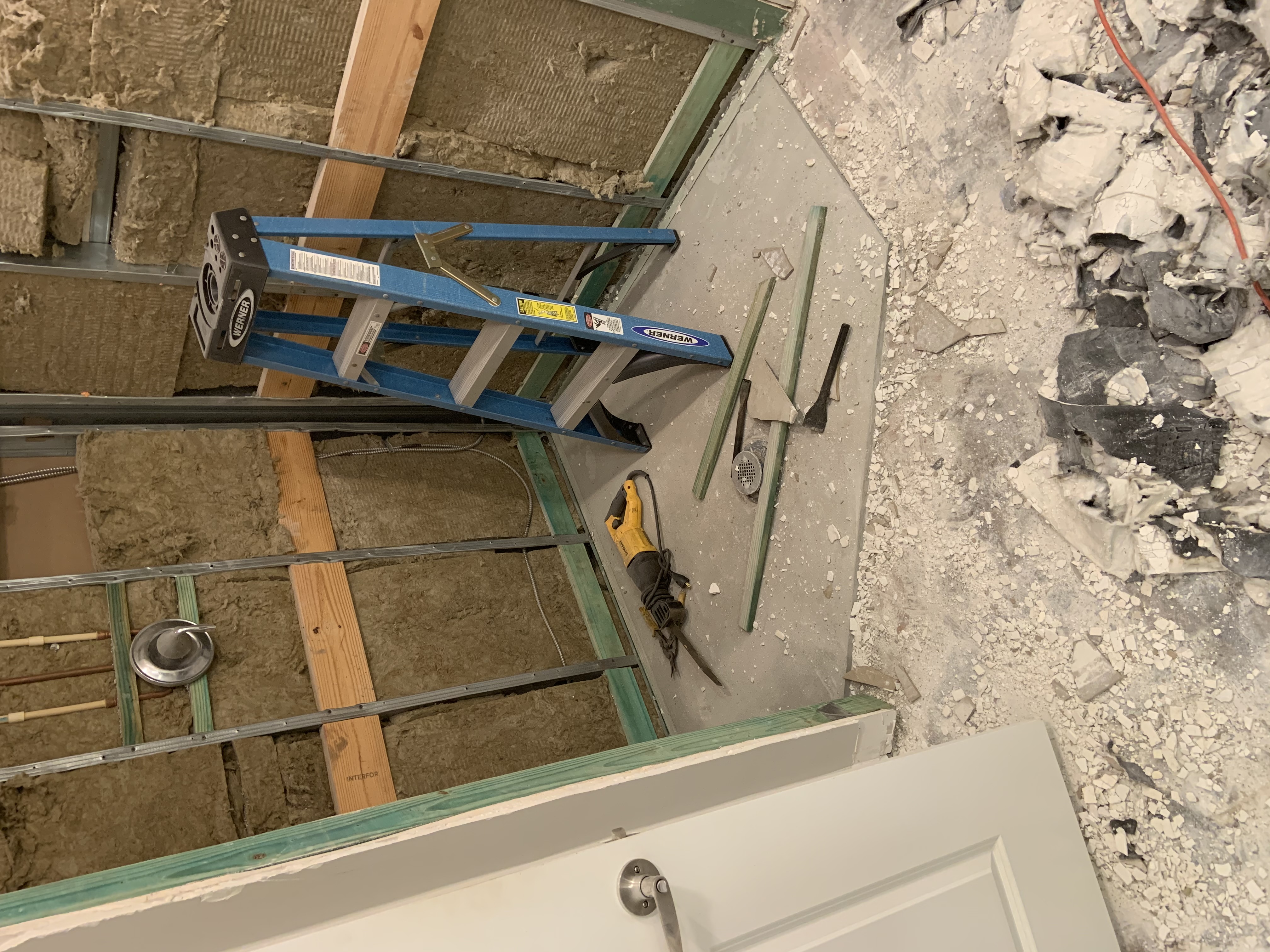Bathroom shower area during demolition with framing and wall materials exposed