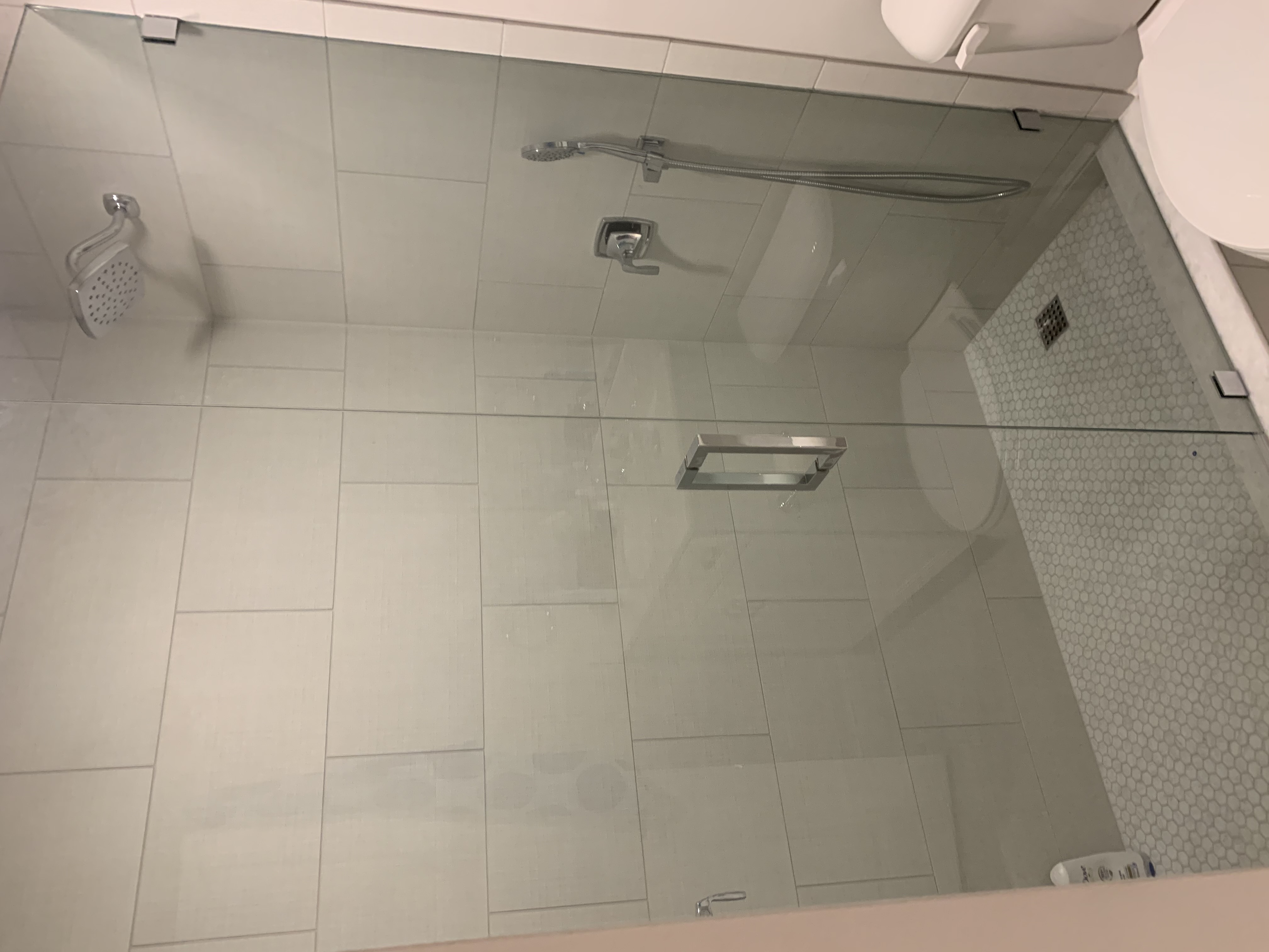 Finished shower from another angle showing the glass panel and completed tile work