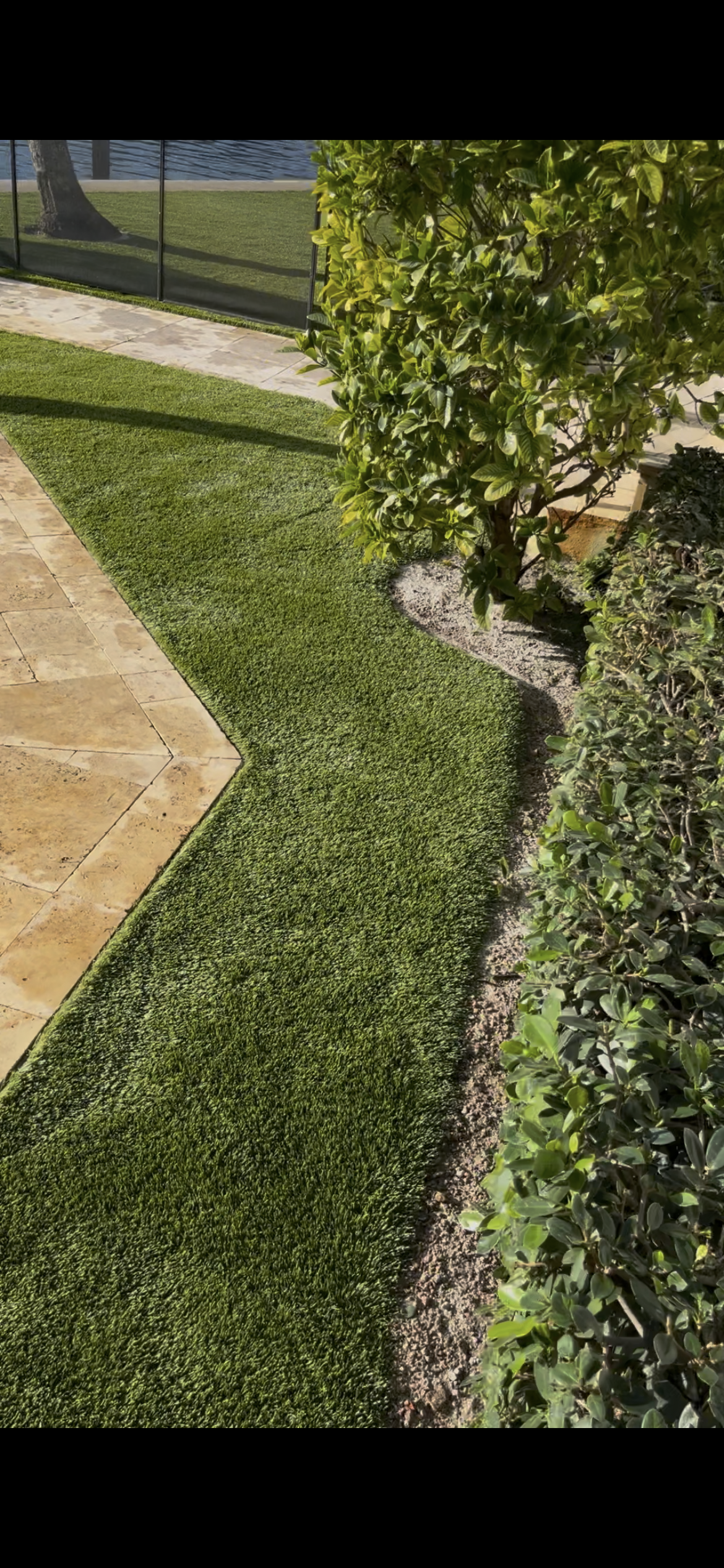 Finished artificial turf installed neatly along the patio edge and planting bed